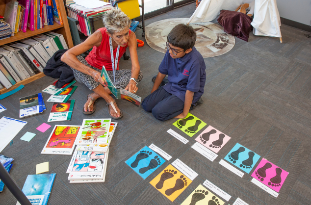 Boy working one on one with a teacher to read at The Winston School, a learning different school in Dallas, Texas.